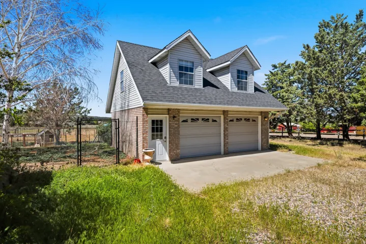 Two-car garage with overhead doors, brick and siding exterior, dormer windows, and a black shingled roof
