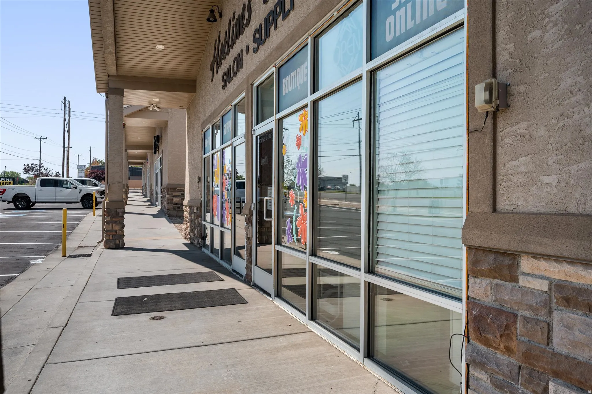 Storefront with large display windows, textured stucco exterior, stone-clad columns, covered walkway, and recessed lighting
