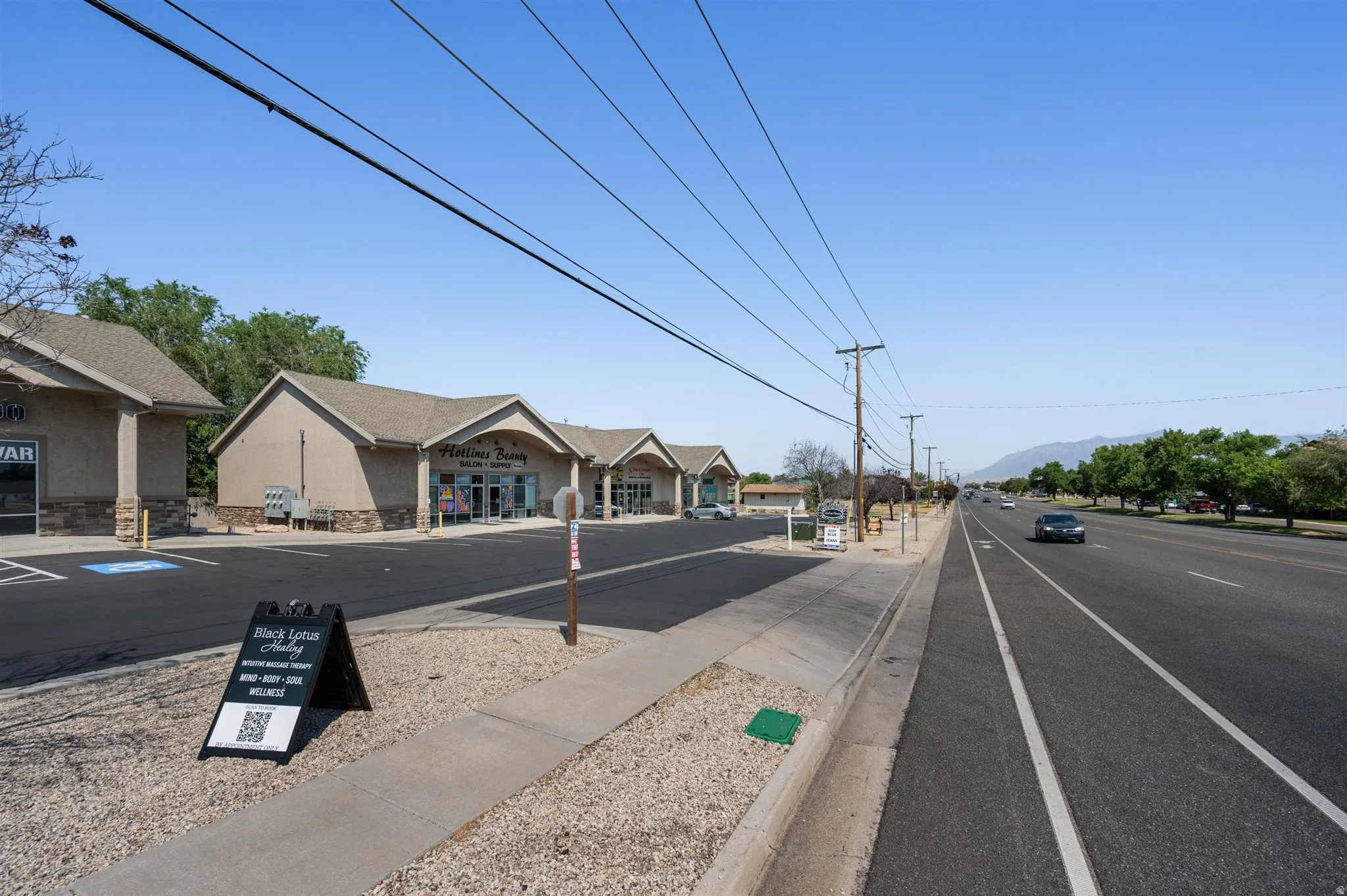 Commercial complex featuring multiple storefronts, paved parking, and direct frontage on 1900 W. Looking North