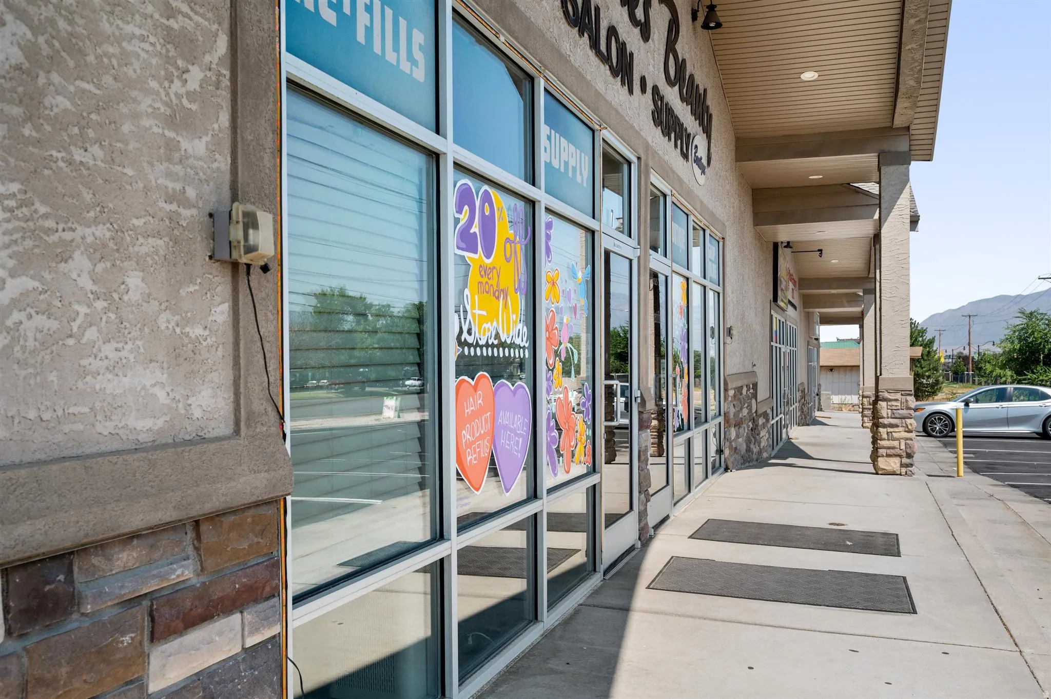Storefront with large glass display windows, stucco exterior, stone veneer accents, and a covered walkway