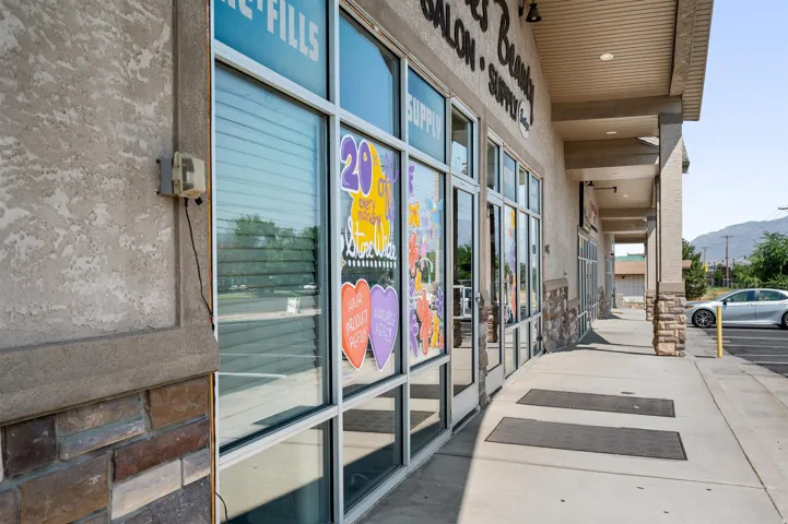 Storefront with large glass display windows, stucco exterior, stone veneer accents, and a covered walkway