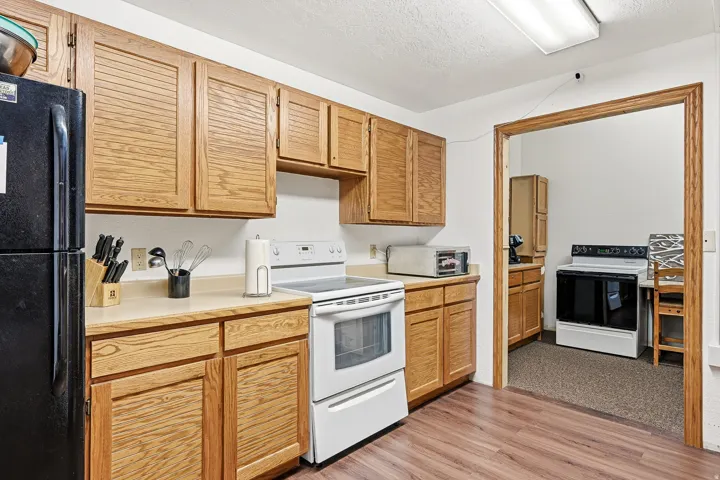 Kitchen featuring wood-finish cabinetry, solid surface countertops, a white electric range, and wood-finish flooring