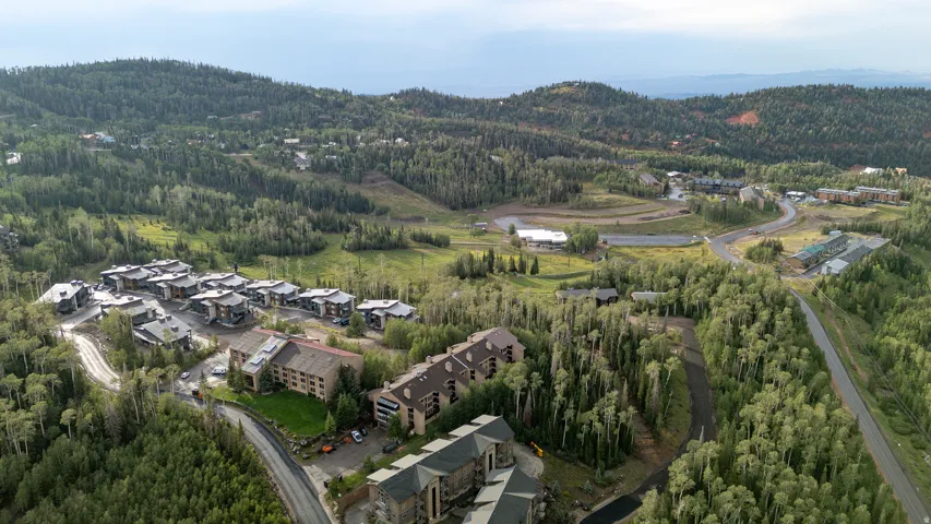Expansive elevated property featuring multiple residential structures, surrounded by abundant mature trees and winding paved roads