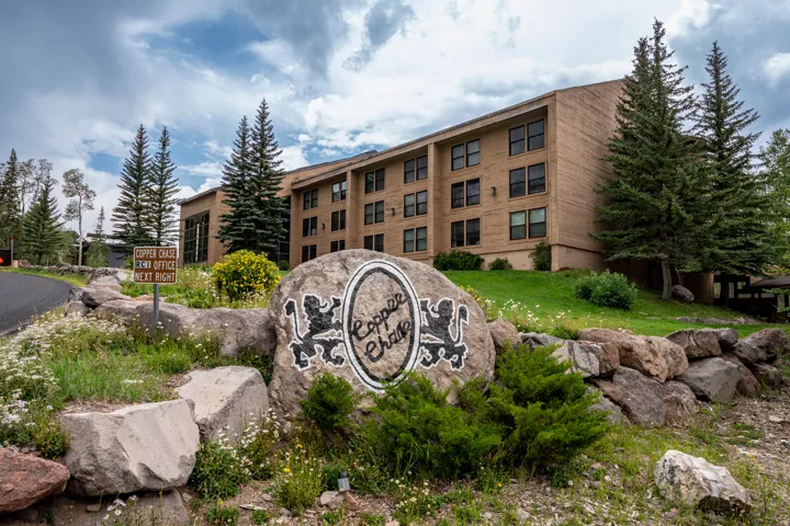 Welcoming brick and stone exterior with mature evergreen landscaping and natural boulder accents