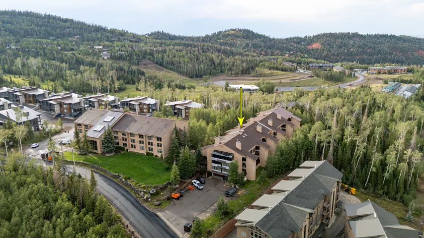 Multi-story property featuring a sloped roofline, multiple balconies, and a mountain setting