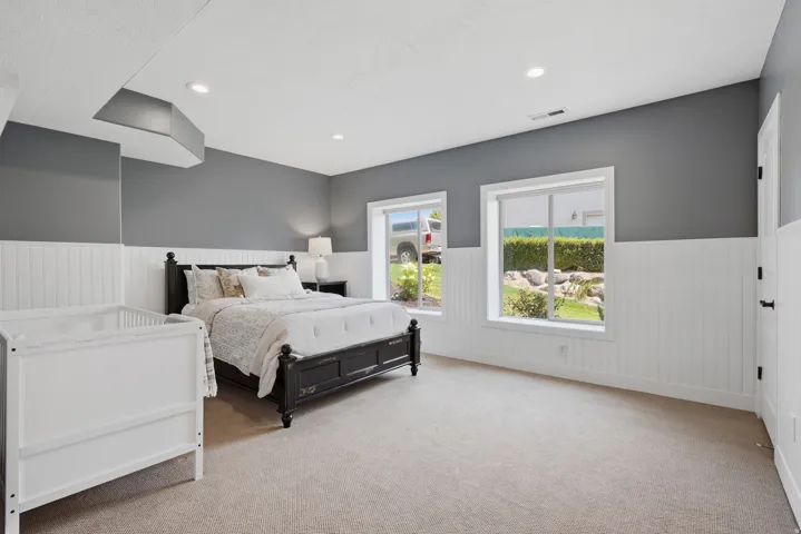 Primary bedroom featuring a black metal bed frame, white beadboard wainscoting, gray upper walls, and recessed ceiling lighting