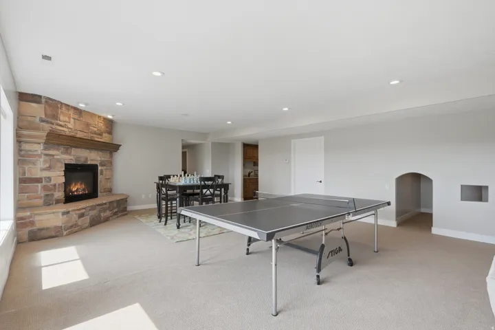 Spacious lower level featuring a stone-clad fireplace with a wood mantel, recessed lighting, and soft carpeting
