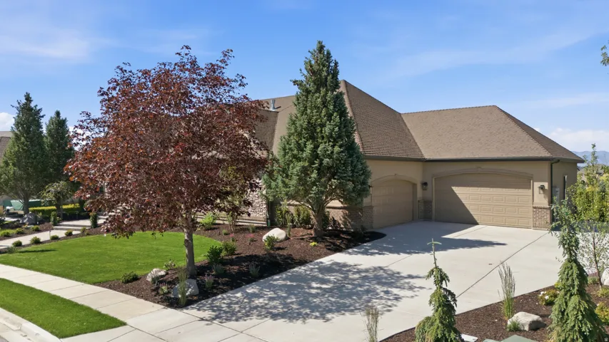 Stucco exterior with stone accents, concrete driveway, and attached garage