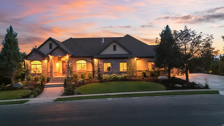 Stone and stucco exterior with arched windows, a multi-pitch roof, and an inviting walkway leading to the entry