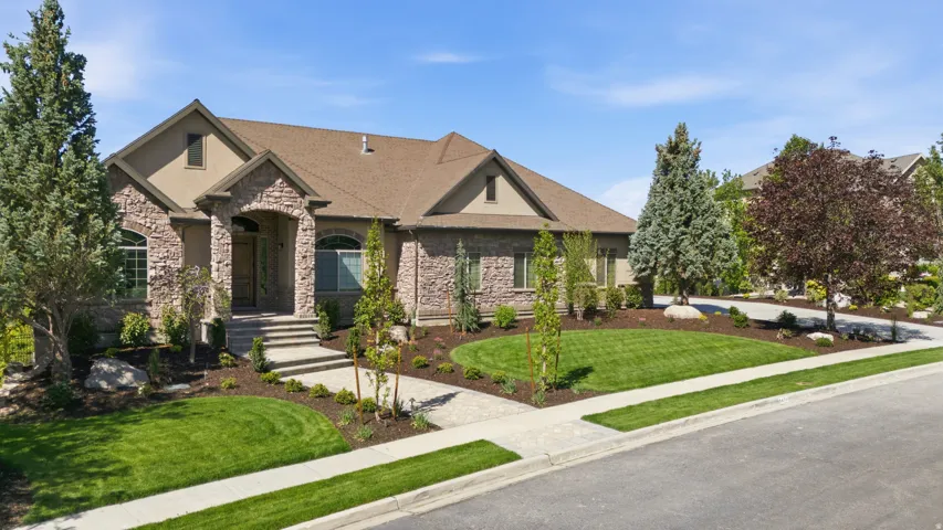 Stone and stucco exterior with an arched entryway, gabled roof, and a paved driveway