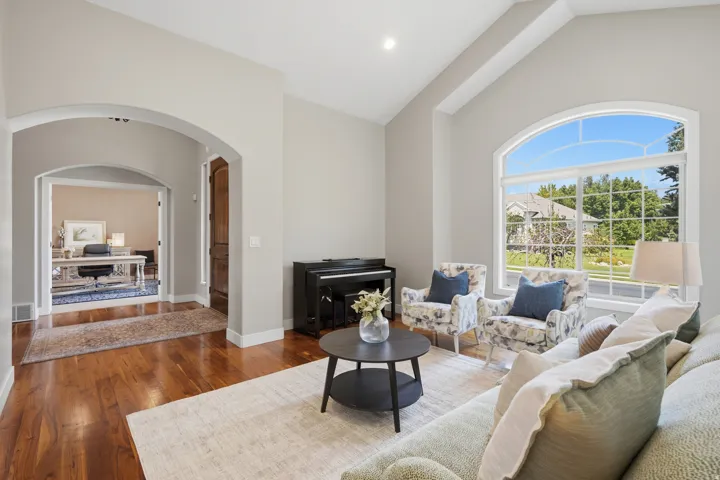 Sophisticated living room showcasing soaring ceilings, arched architectural details, and abundant natural light from expansive arched windows framing outdoor scenery