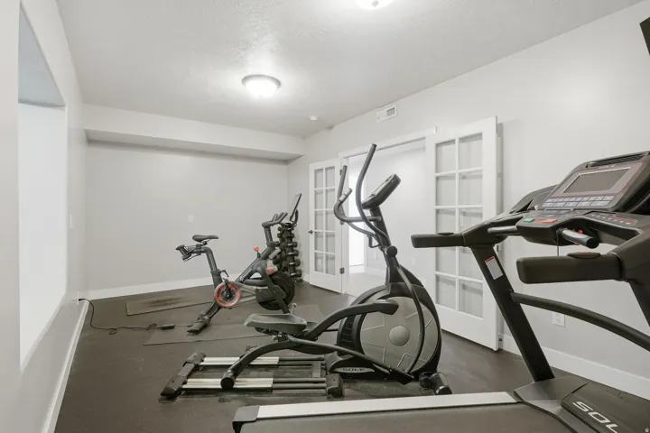 Dedicated fitness room featuring polished concrete flooring, recessed ceiling lighting, and glass French doors