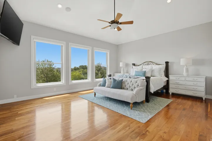 Vaulted ceiling with a ceiling fan, recessed lighting, wood-finish flooring, and multiple windows