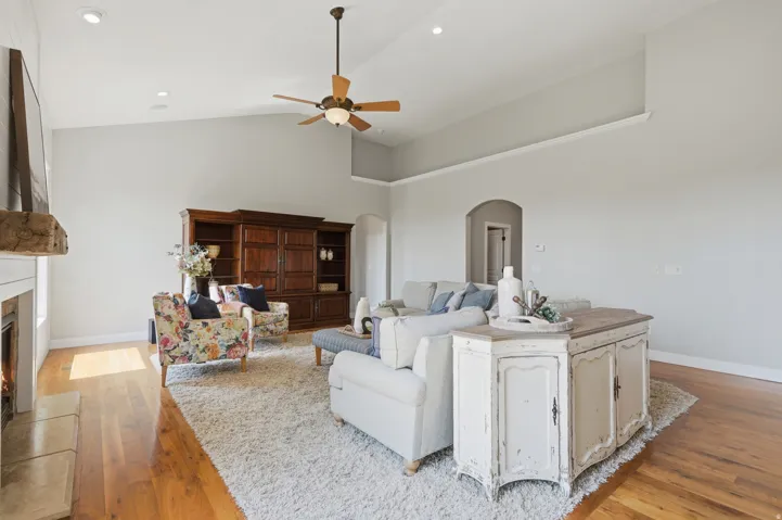 Vaulted ceiling with a ceiling fan, recessed lighting, hardwood flooring, and an arched doorway