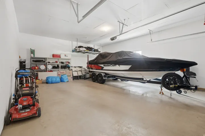 Spacious climate-controlled garage with epoxy-finish concrete flooring, overhead storage systems, and capacity for multiple vehicles and watercraft