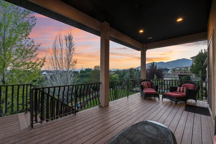 Covered outdoor deck with composite decking, decorative metal railings, recessed lighting, and support columns