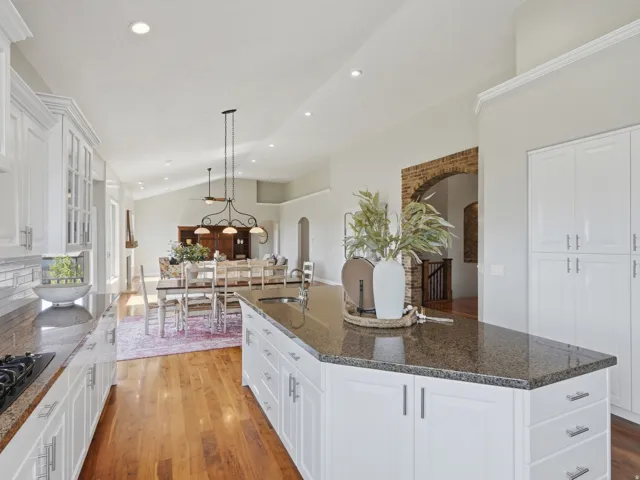 Spacious kitchen with white cabinetry, granite countertops, and hardwood flooring