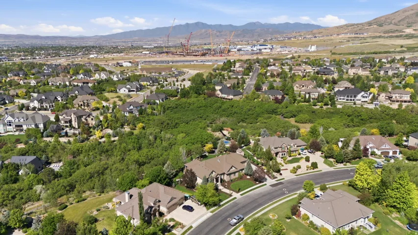 Aerial perspective showcasing a substantial residential estate nestled within a mature tree-lined neighborhood, featuring a curved driveway, multi-car garage, and manicured grounds