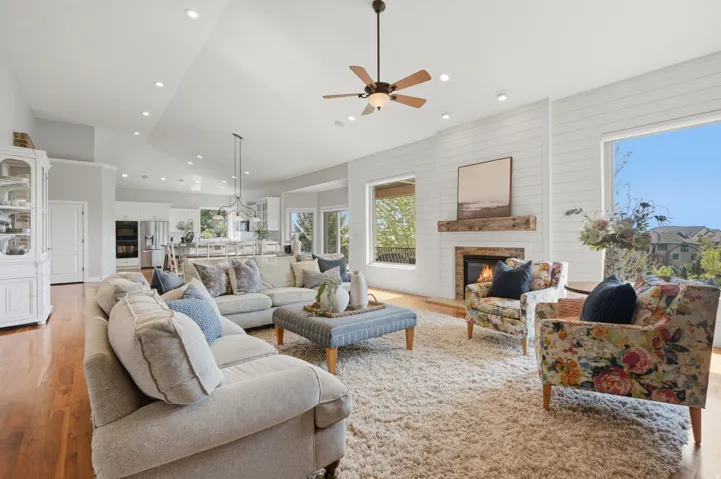 Spacious living room anchored by a linear fireplace with shiplap surround, hardwood flooring throughout, and abundant natural light from expansive windows