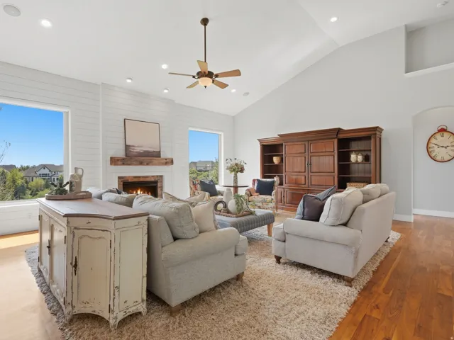 Living area with hardwood-finish flooring, vaulted ceiling, recessed lighting, and a stone fireplace with a wood mantel