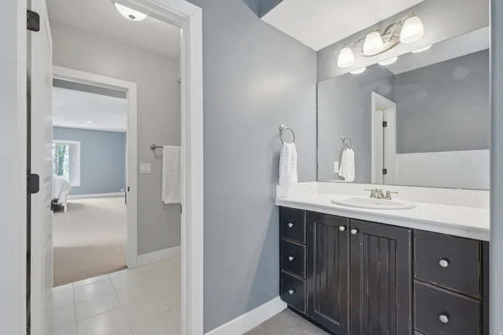 Bathroom vanity with a white countertop, undermount sink, and a large wall-mounted mirror