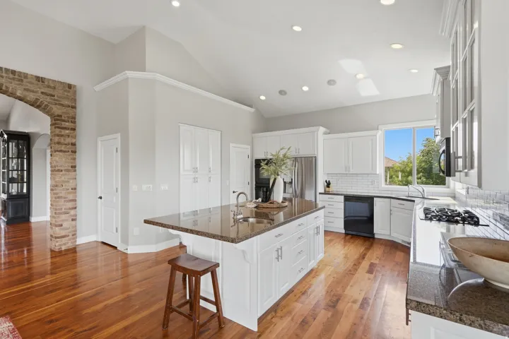 Chef's kitchen featuring white cabinetry, a large center island with wood-finish countertop, stainless steel appliances, recessed ceiling lighting, and hardwood flooring throughout