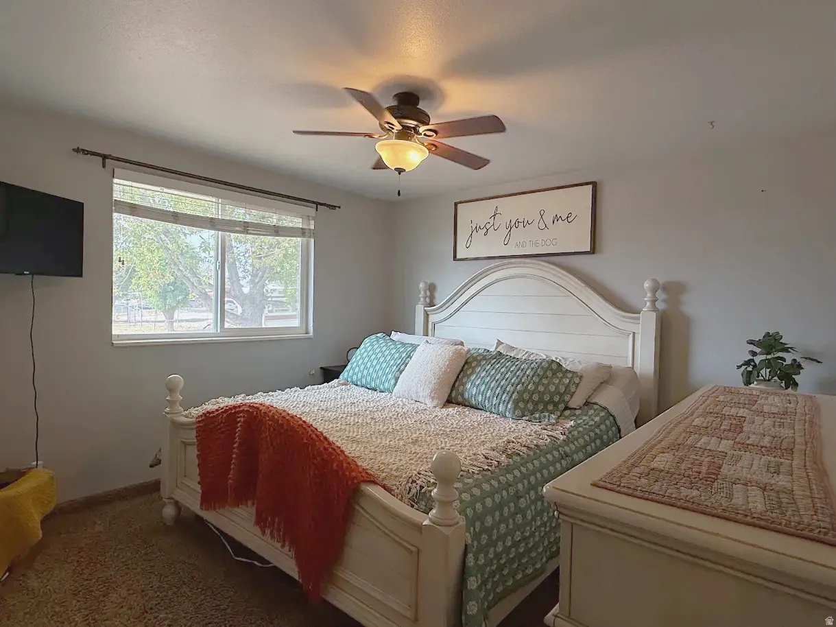 Neutral wall color, ceiling fan with integrated lighting, window with a natural wood-look frame, and light-colored carpeting