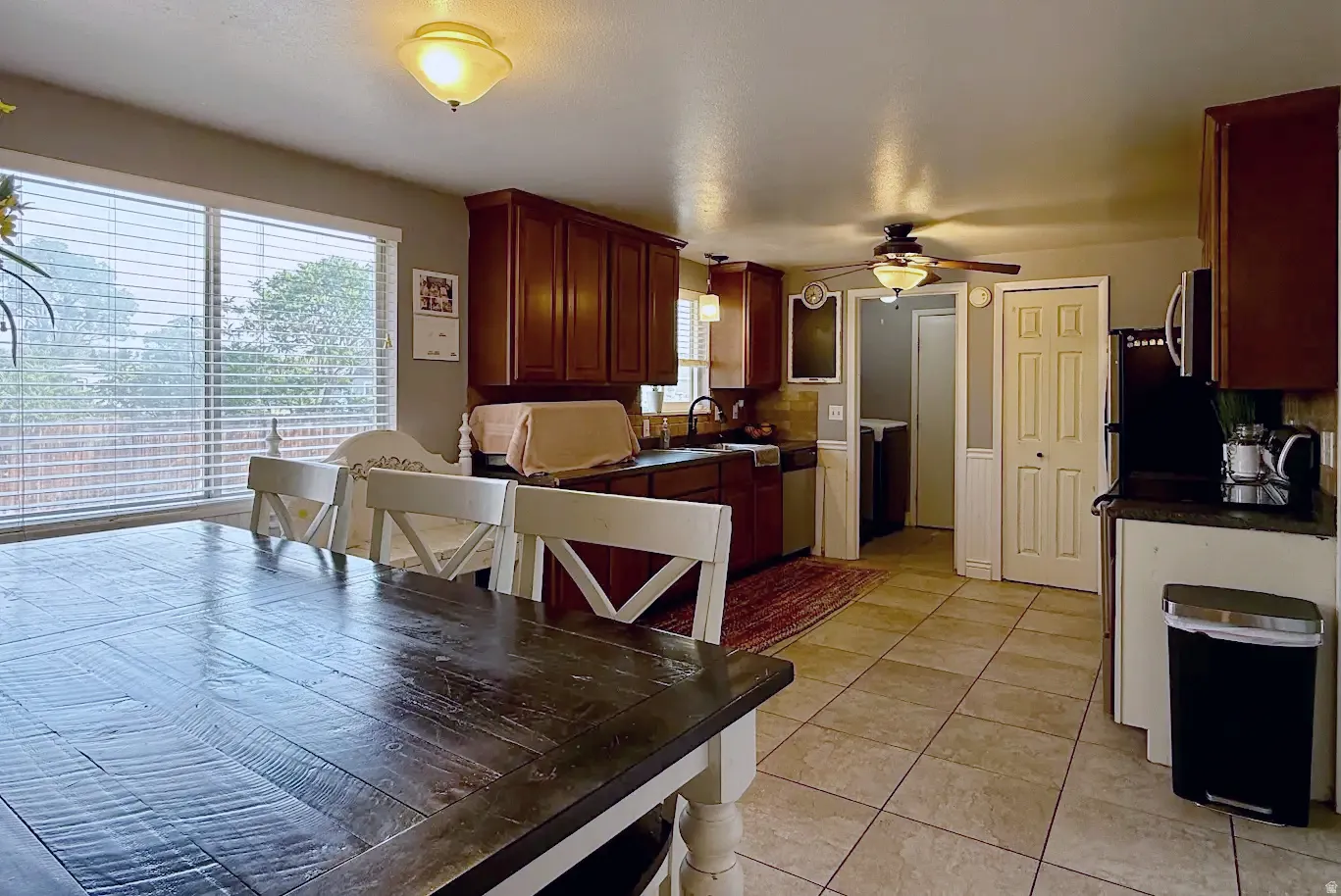 Kitchen with wood cabinetry, tile flooring, a large window, a ceiling fan, and built-in appliances