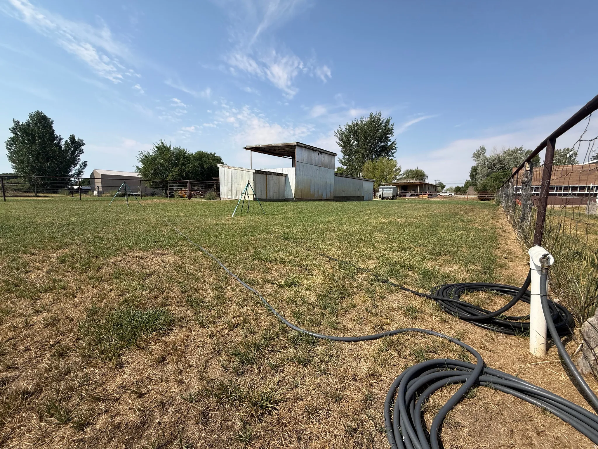 Expansive outdoor space featuring a detached outbuilding and perimeter fencing