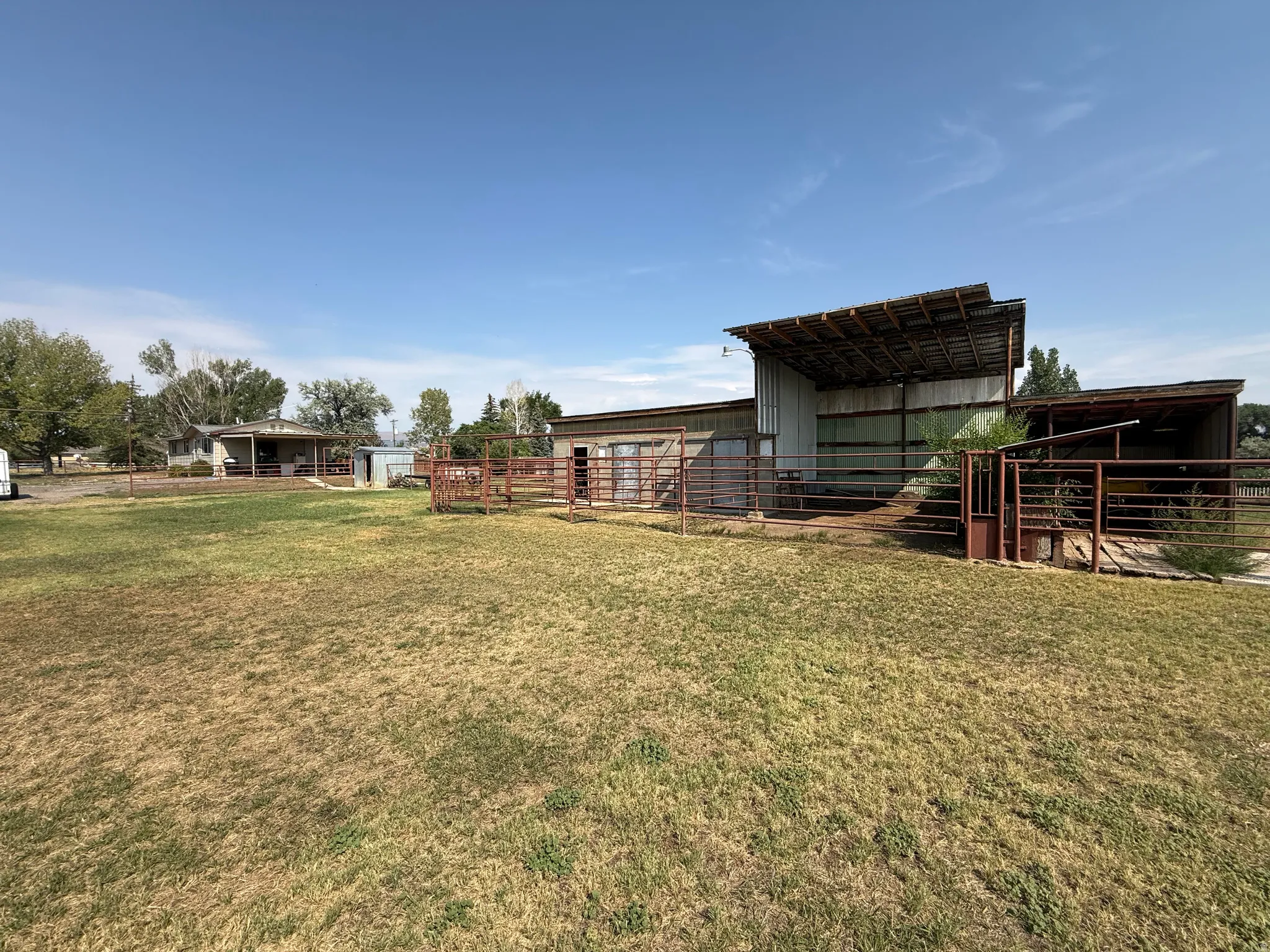 Metal-sided outbuilding with an open-sided shed structure, an additional attached covered structure, and metal fencing