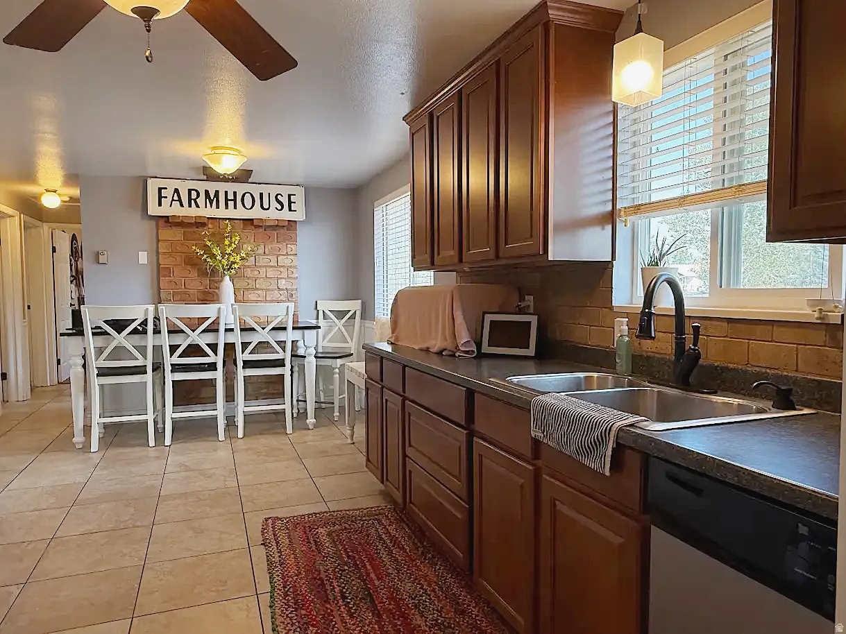Kitchen featuring dark wood cabinetry, a double basin sink, and a dishwasher