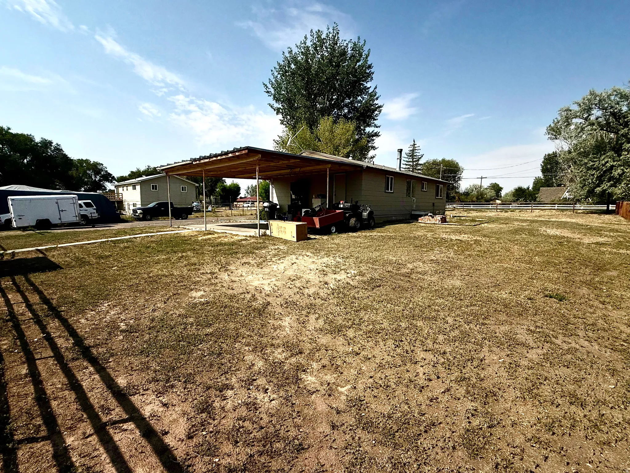Expansive outdoor space featuring a covered patio, a large open yard, and mature trees