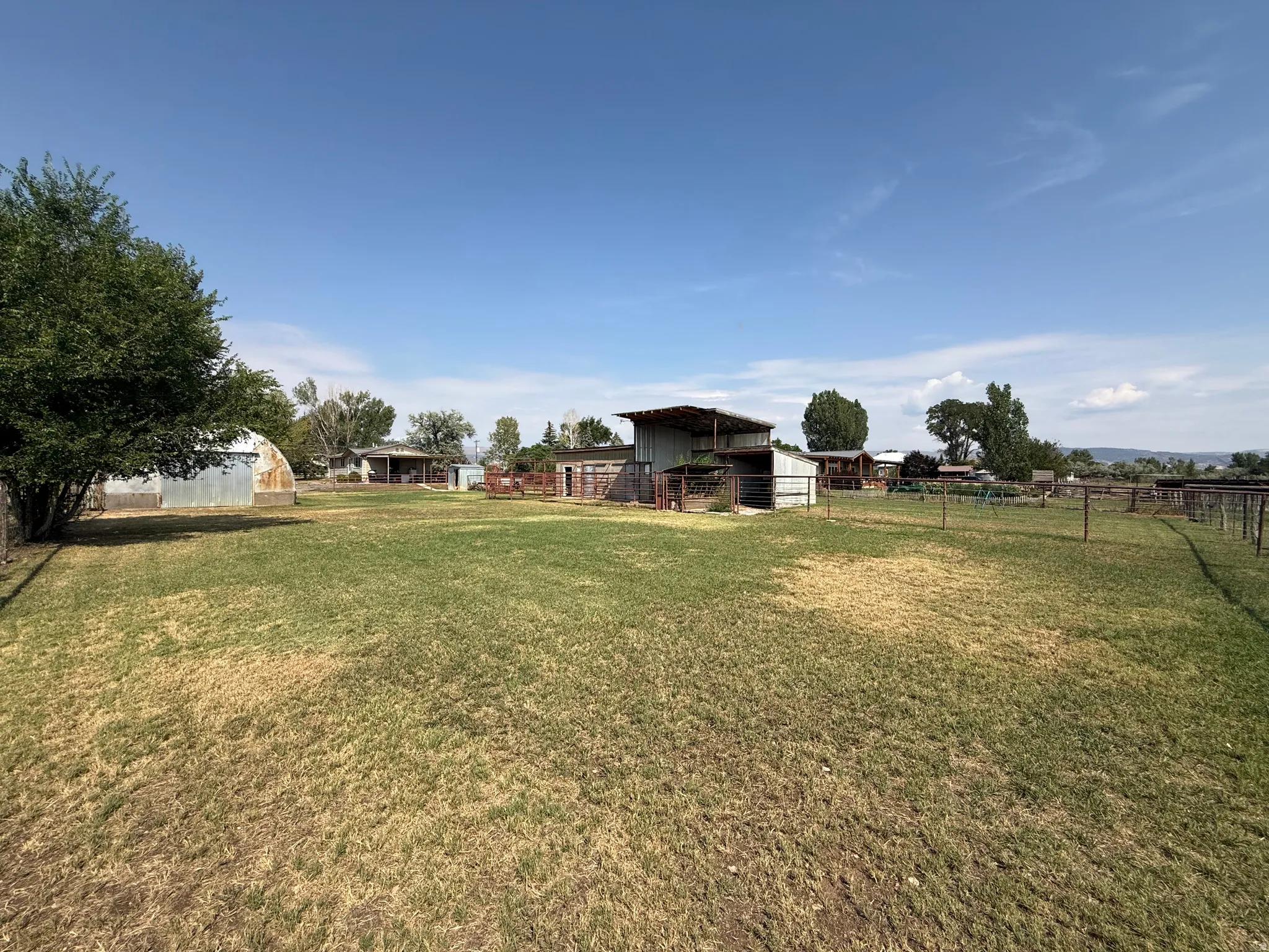 Expansive grassy area with multiple outbuildings and perimeter fencing