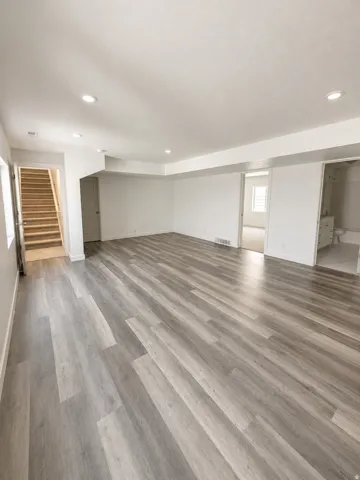 Spacious room with wood-finish flooring, recessed lighting, and white painted walls