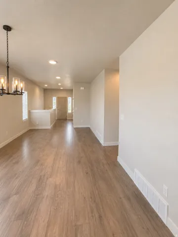 Spacious room featuring wood-finish flooring, recessed lighting, and a contemporary chandelier