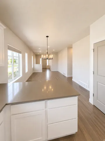 Open-concept kitchen and dining area featuring a large center island with white cabinetry, quartz countertop, and pendant lighting