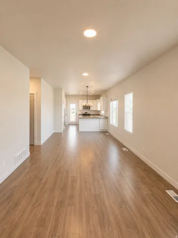 Open-concept living area featuring wood-finish flooring, recessed lighting, and multiple windows with blinds