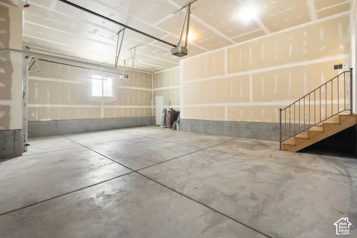 Spacious garage featuring a concrete floor, window, and unfinished drywall walls