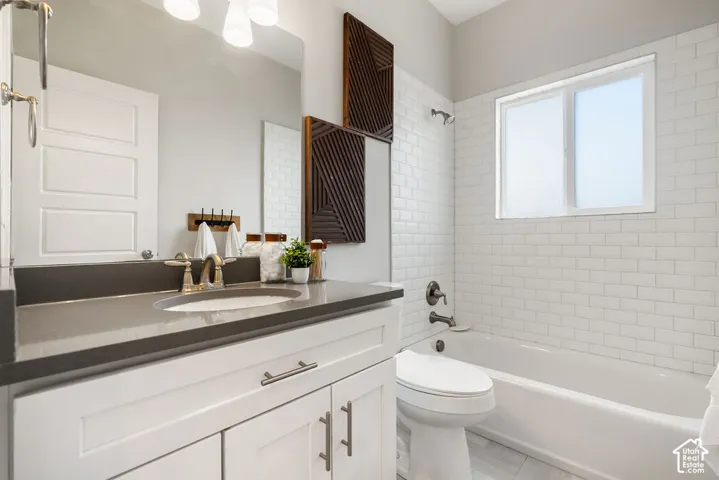 Spa-inspired bathroom featuring a white subway tile surround, floating vanity with dark countertop and dual handles, recessed lighting, and an integrated soaking tub with shower combination