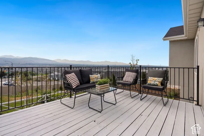 Expansive composite decking spans the entire outdoor living space, anchored by a black metal railing system and framed by mountain vistas