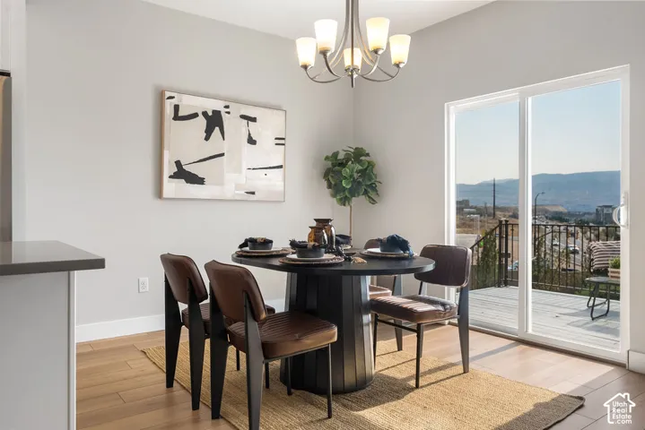 Spacious dining area with wood-finish flooring, a contemporary chandelier, a sliding glass door, and an exterior deck