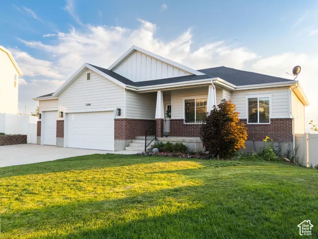 Charming single-story residence featuring a brick and siding exterior with a two-car attached garage, covered front porch with columns, and gabled roofline