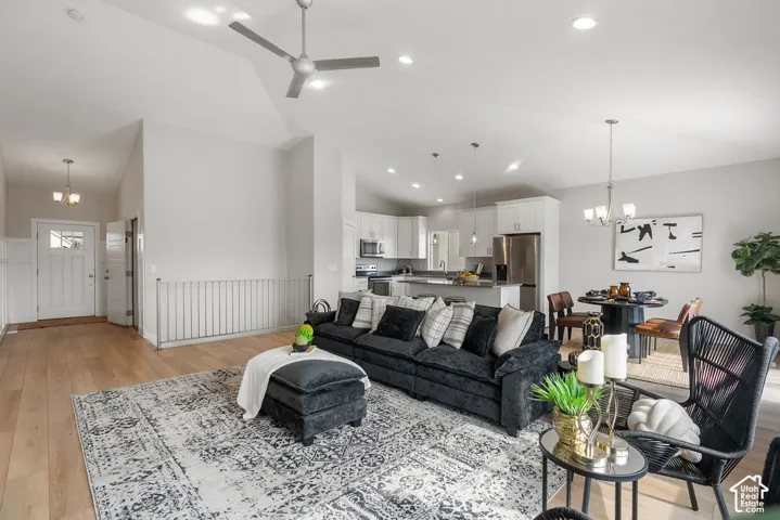 Vaulted ceilings, wood-finish flooring, white kitchen cabinetry, stainless steel appliances, and a kitchen island