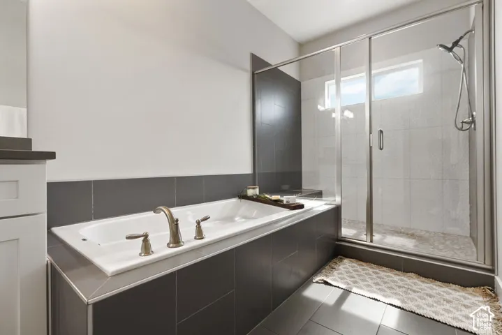 Soaking tub with brushed nickel fixtures, glass-enclosed shower, dual showerhead, and transom window