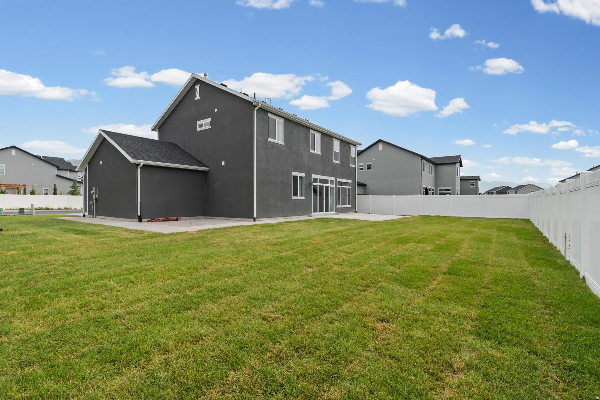 Expansive backyard with a manicured lawn, full vinyl privacy fencing, and a concrete patio