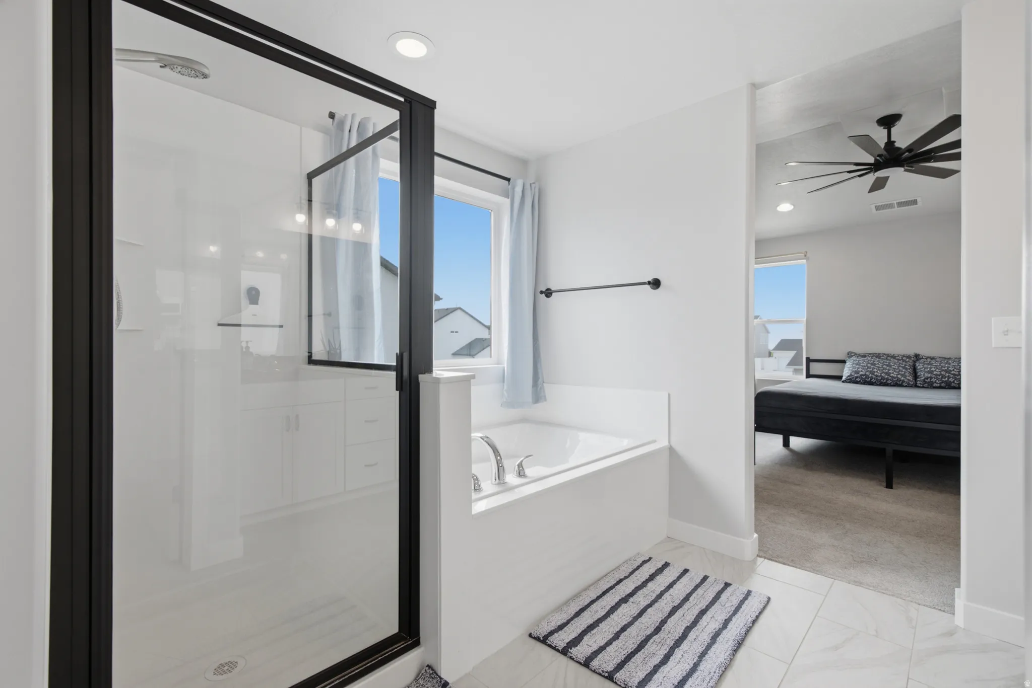 Bathroom featuring a glass-enclosed shower with black trim, a built-in soaking tub, and tile flooring