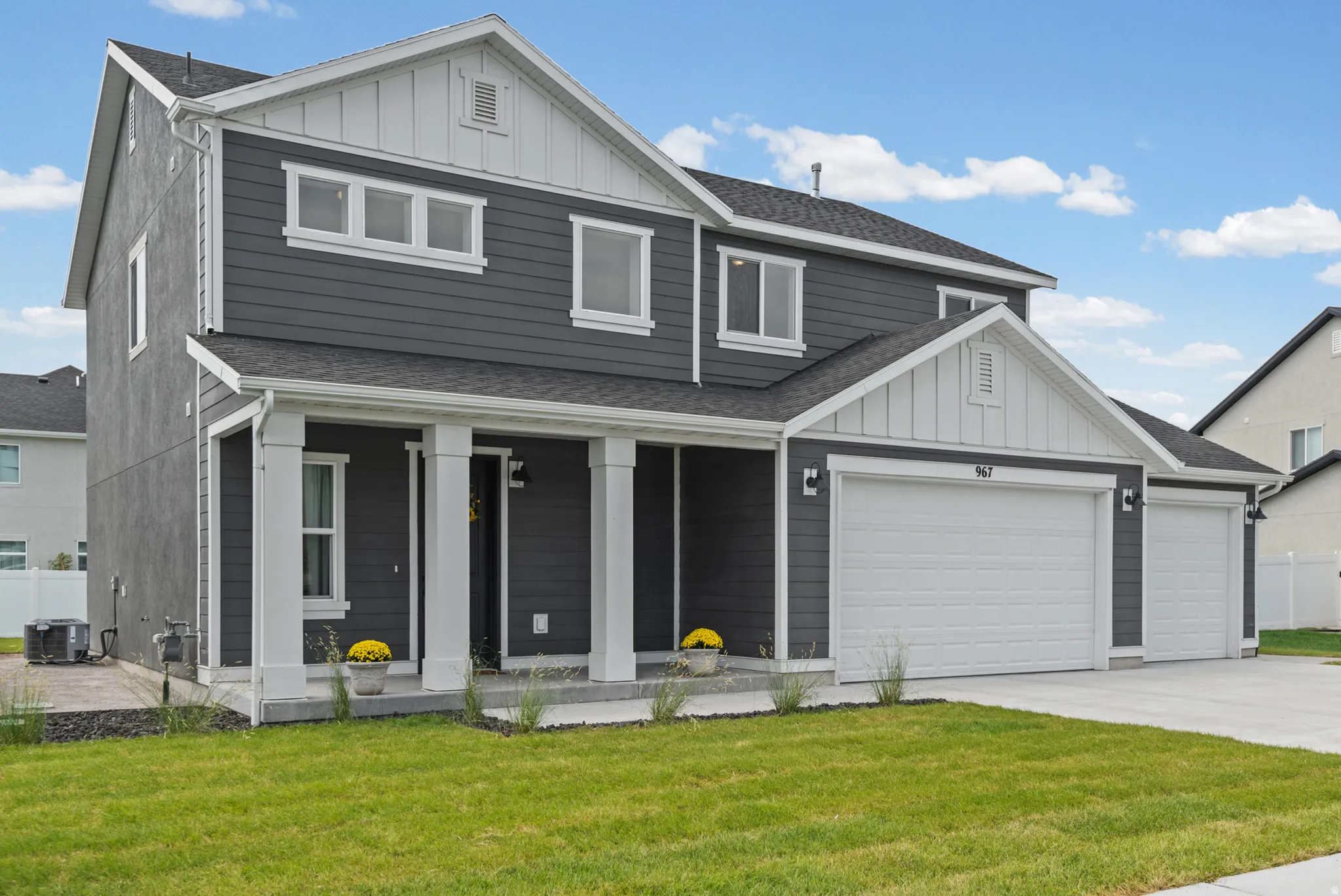 Modern two-story home featuring a charcoal gray exterior with contrasting white trim, multiple windows allowing natural light throughout, and a covered front porch with white columns