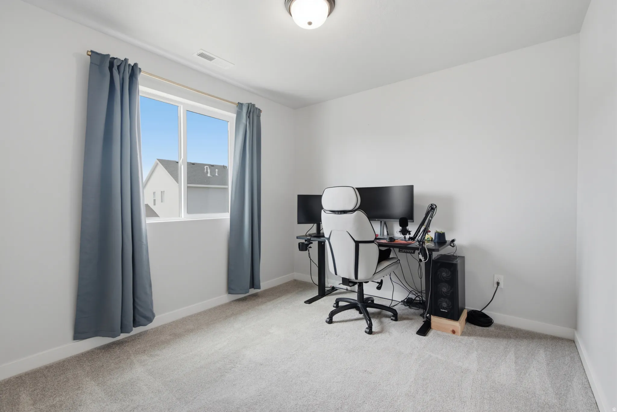 Neutral wall tones, carpeted flooring, and a single window with a light fixture