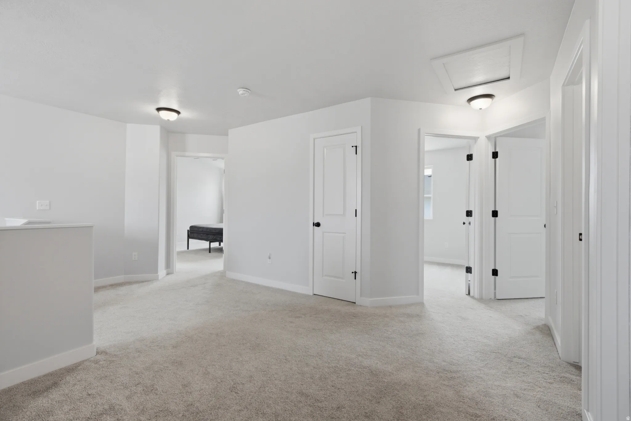 Bright, open primary suite featuring neutral carpeting, multiple closet spaces with glass-panel doors, and recessed ceiling lighting throughout
