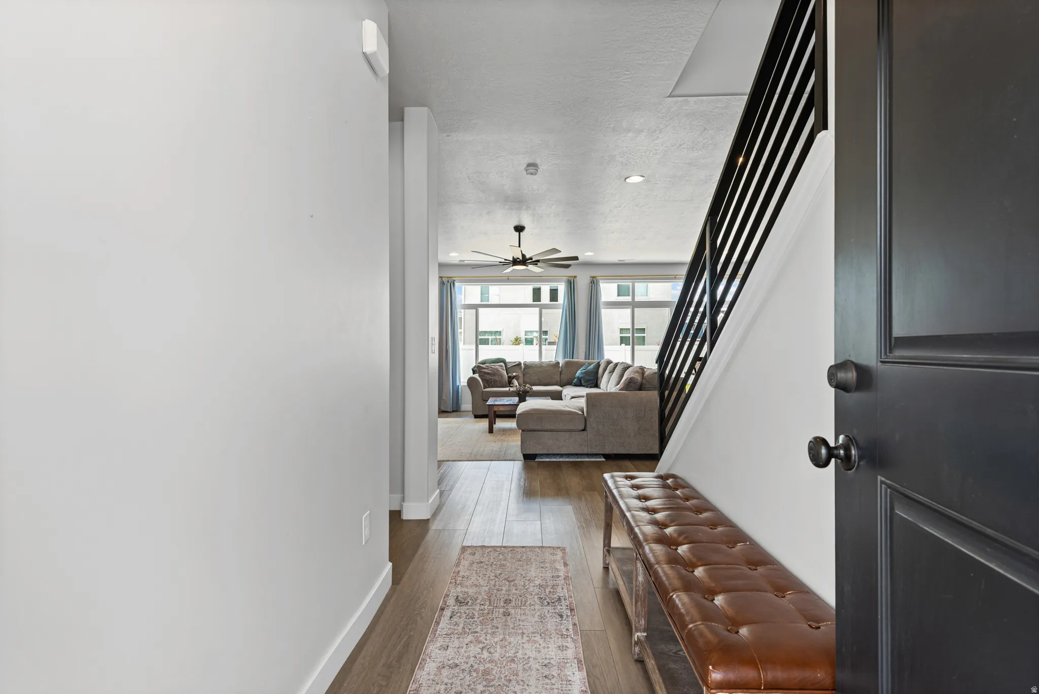 Entryway featuring wood-finish flooring, a contemporary staircase with black railings, and a black paneled door